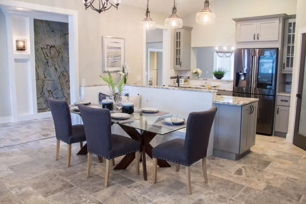 Dining and kitchen area with Parson dining chairs, a set table with wine glasses, and artwork hanging.