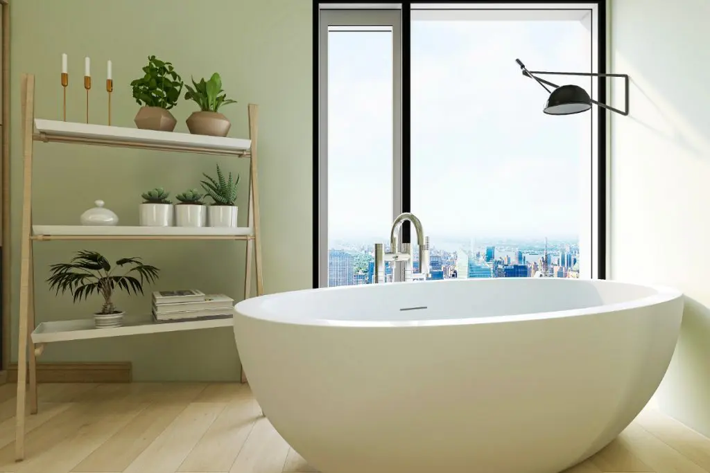 Freestanding bathtub with a view of the city in a light green bathroom