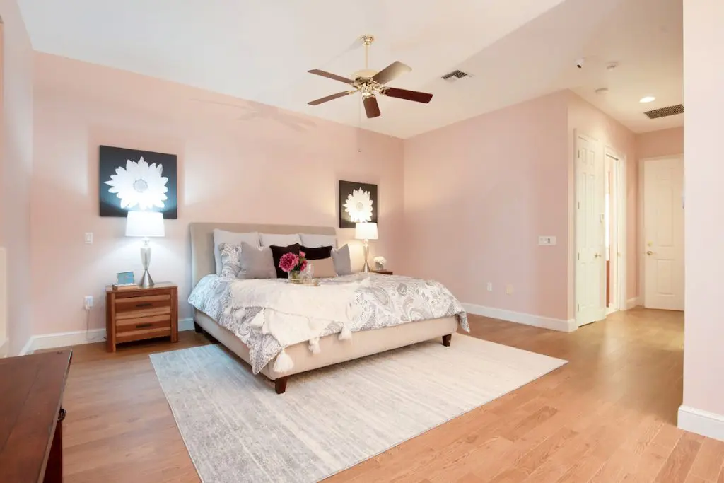 Bedroom with coral walls, wood floors, and wooden nightstands.