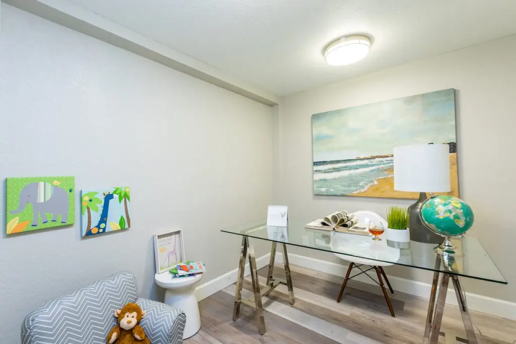 A room that is part office, part playroom with children themed artwork and painted beach canvas staged by MHM Professional Staging for Zombie House Flipping season three episode one.