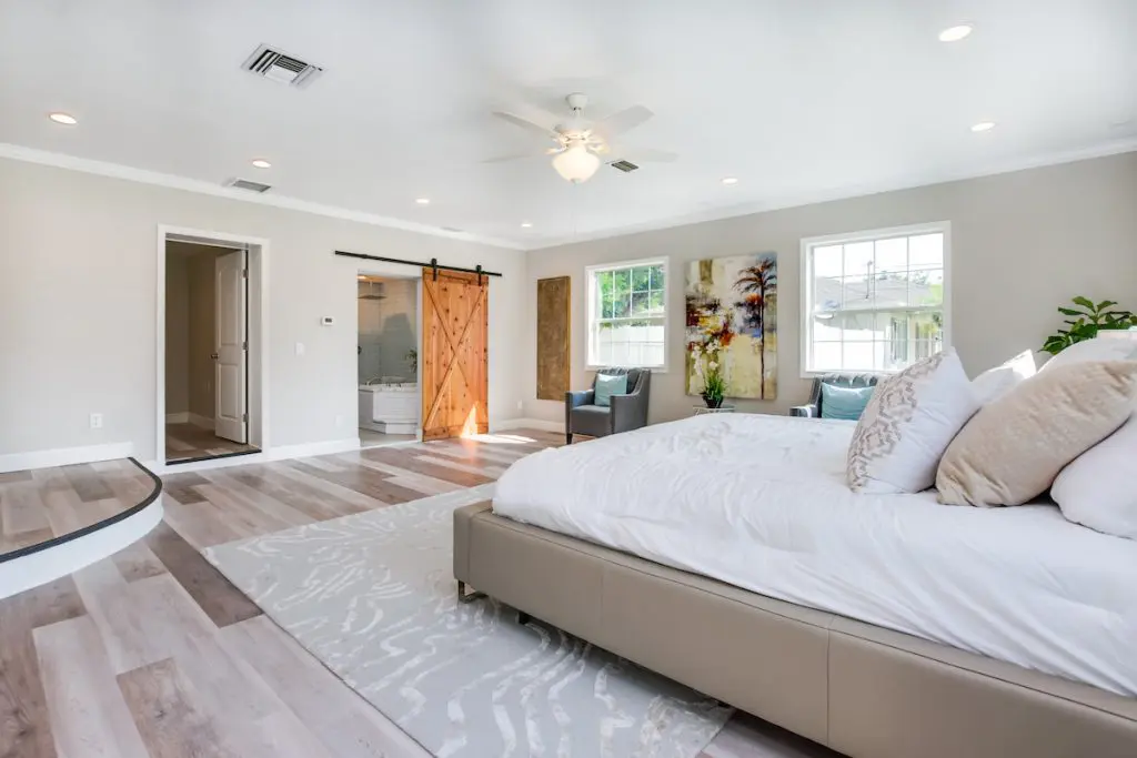 Another view of master bedroom with visible sliding barn door staged by MHM Professional Staging for Zombie House Flipping season three episode one.