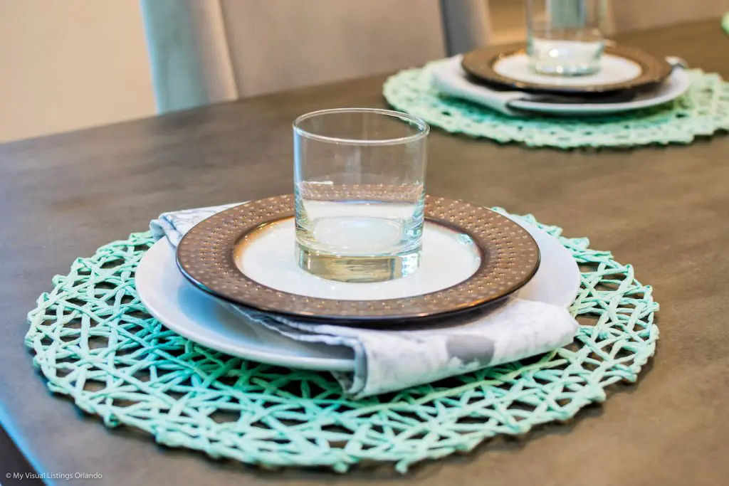 A close up of table setting: placemat, stacked plates, and a glass.