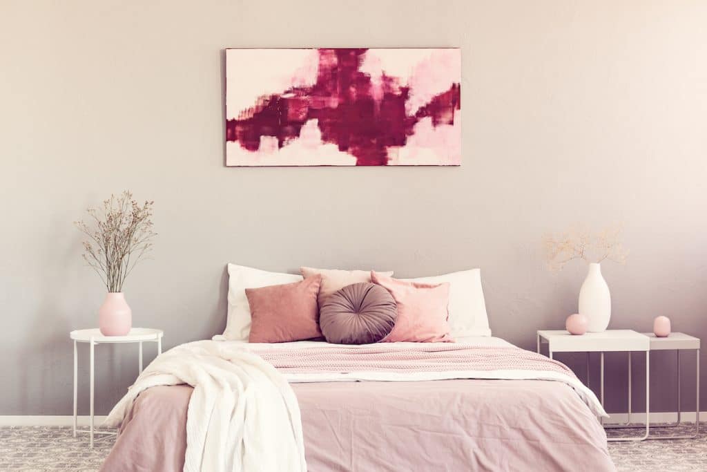 Bedroom with light coral accents like bedspread and vases.