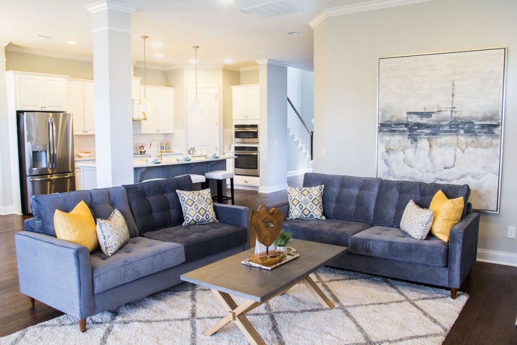 A living room with velvet sofas, a rug, and artwork staged by MHM Professional Staging.